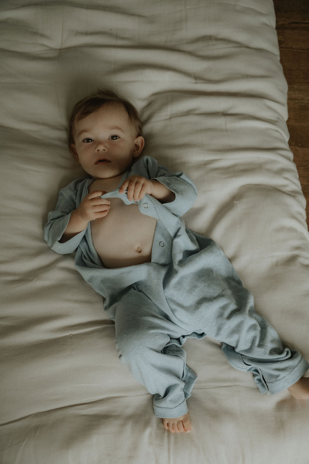 Baby lying on a bed wearing a light blue outfit