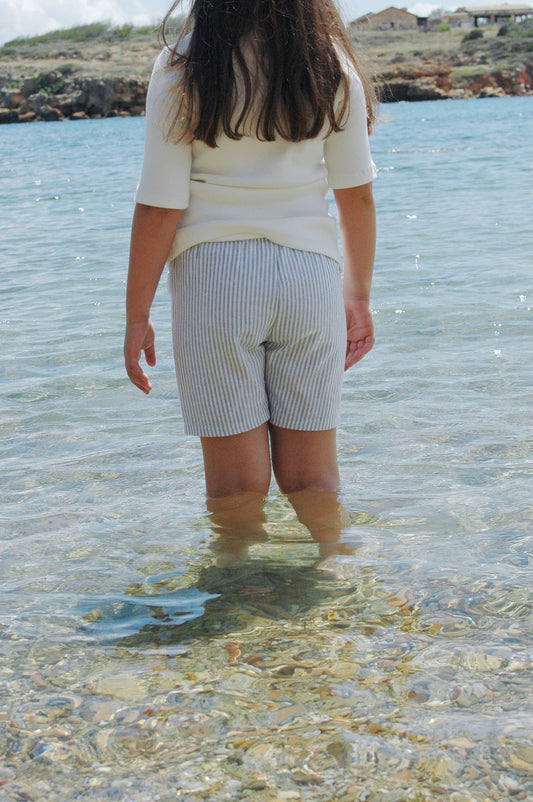 girl in white top stripe shorts in clear blue ocean