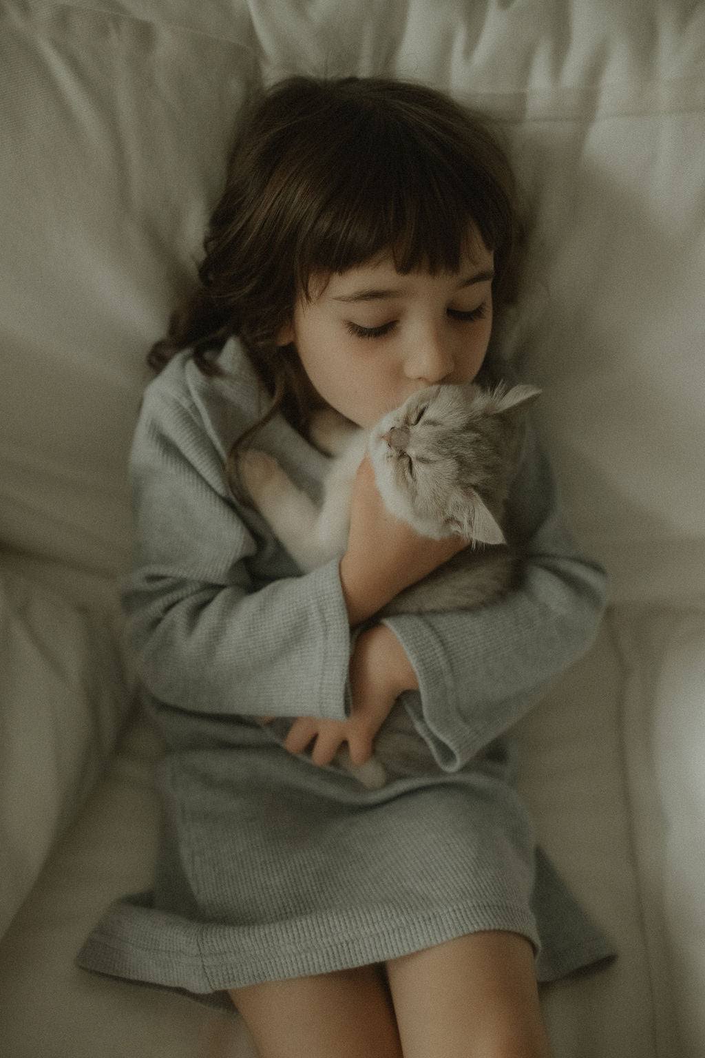 Child holding a cat on a bed