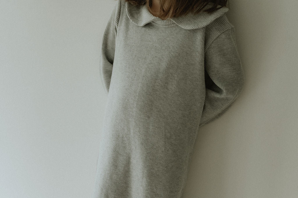 Light gray sweater dress worn by a person against a plain background