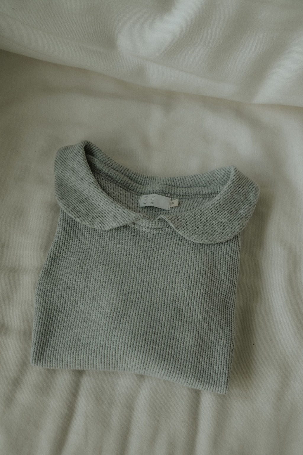Folded green knitted sweater on a beige surface