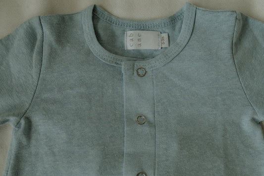 Light blue baby onesie with buttons on a neutral background