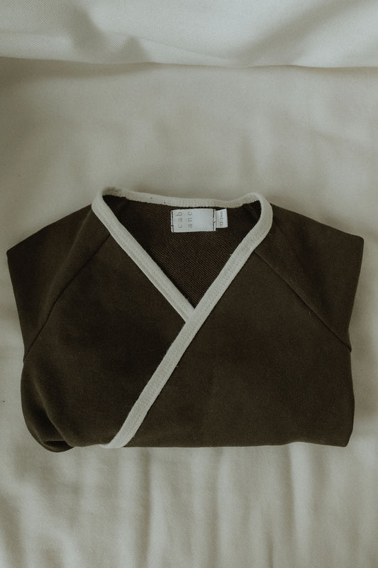 Folded brown kimono style wrap suit with white trim on a light beige background