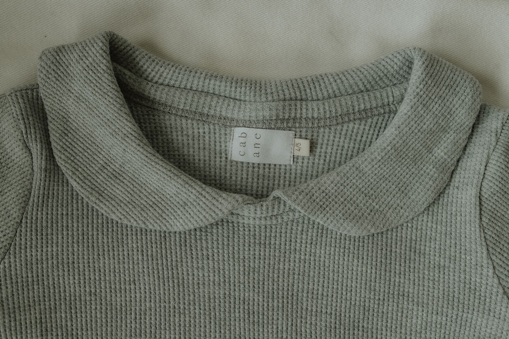 Close-up of a textured gray shirt collar with a label on a light background